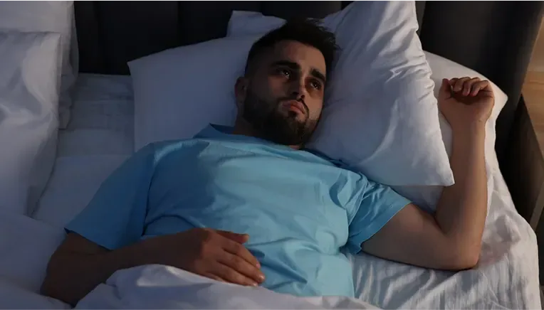 Man lying awake in his bed unable to sleep