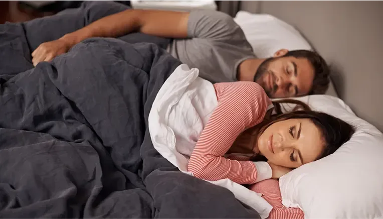 A picture of a couple sleeping comfortably in their bed